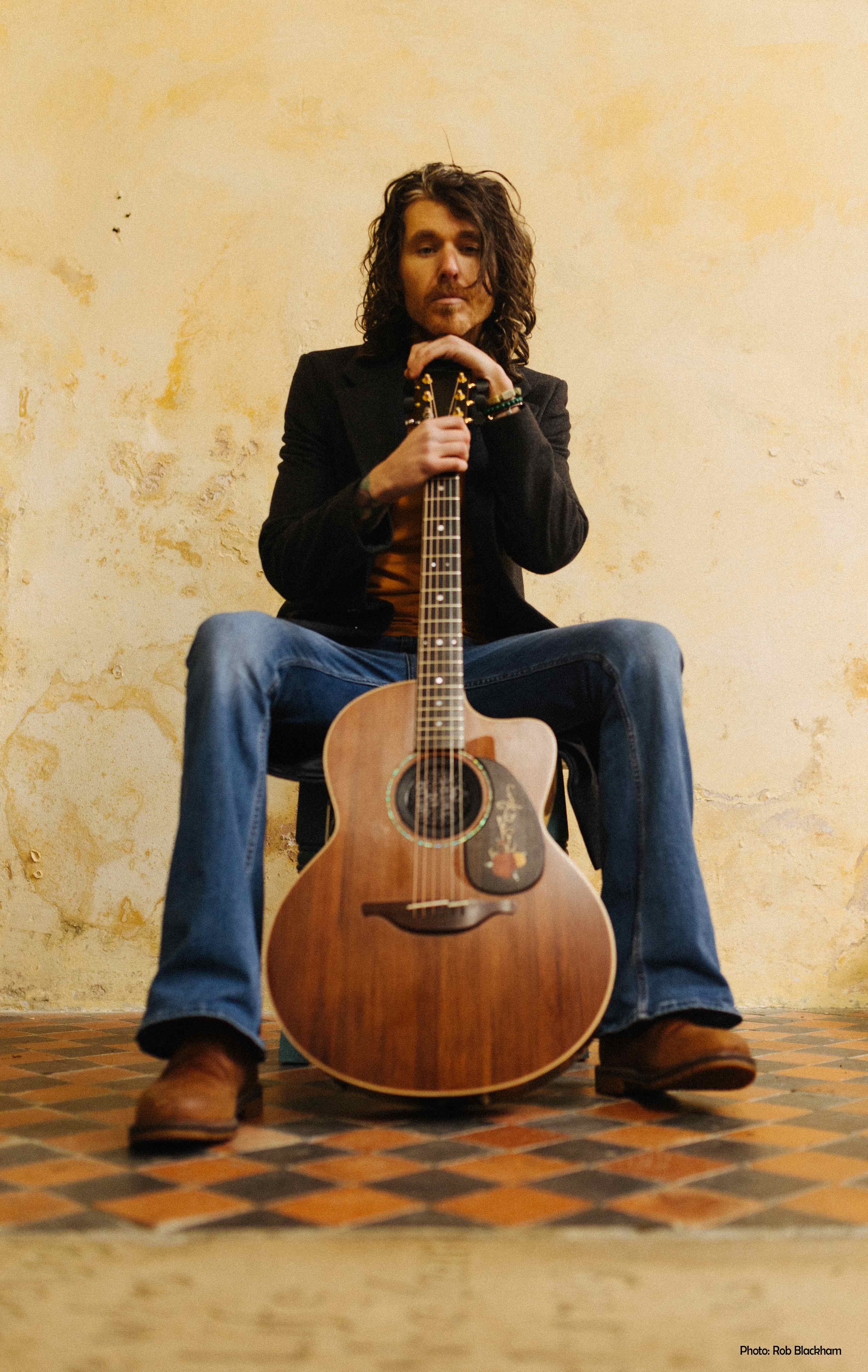 Dom Martin sat on chair with guitar